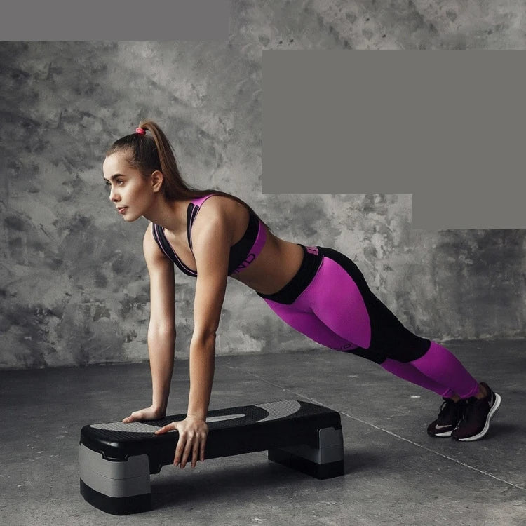 Female athlete using step machine for cardio exercise, weight loss, and home gym fitness workout in purple sportswear
